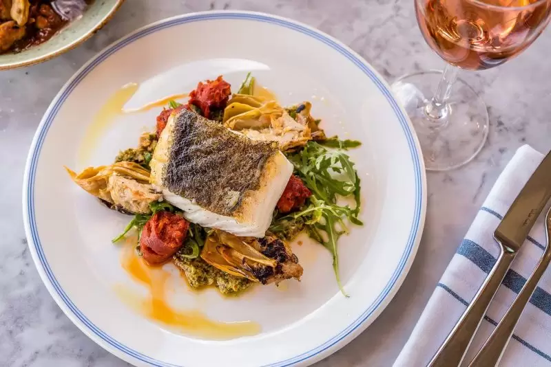 fish on a bed of pesto and salad