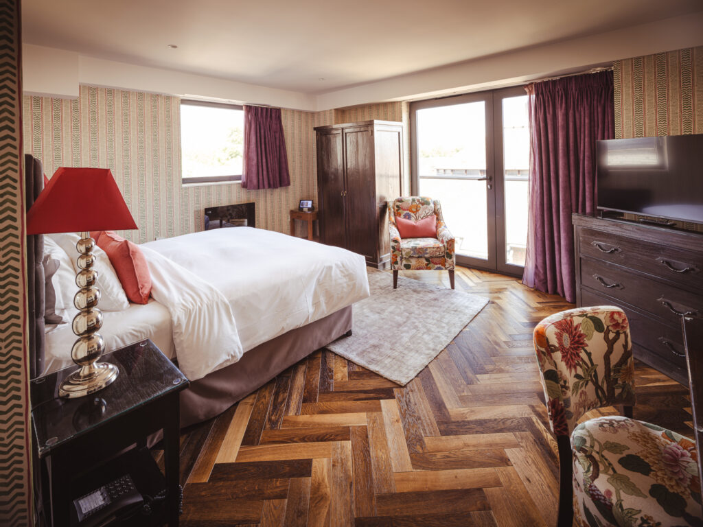 large hotel room with burgundy features and herringbone flooring