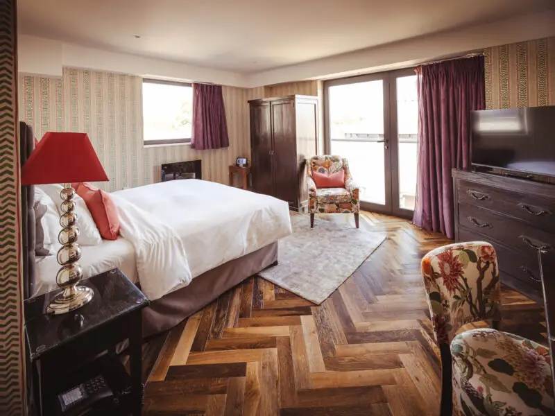 large hotel room with burgundy features and herringbone flooring