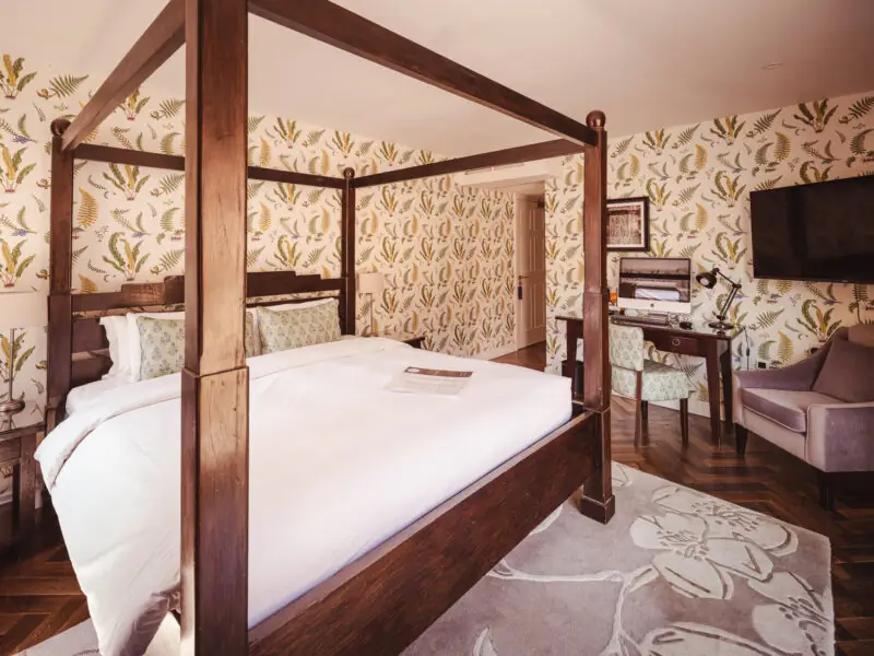 beautiful hotel room with four posted bed and floral wallpaper