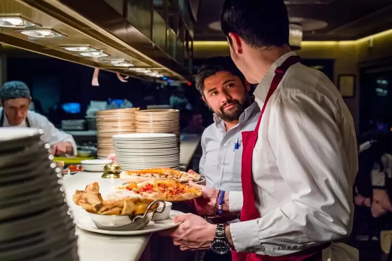 varsity waiters picking up dinners from kitchen to take to customers