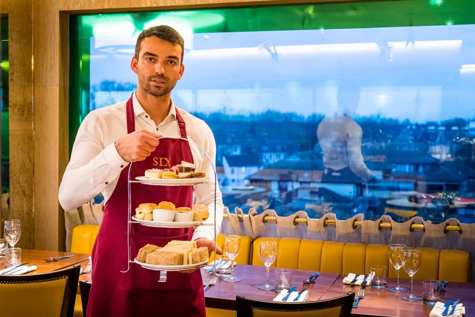 waiter holding afternoon tea in front of window