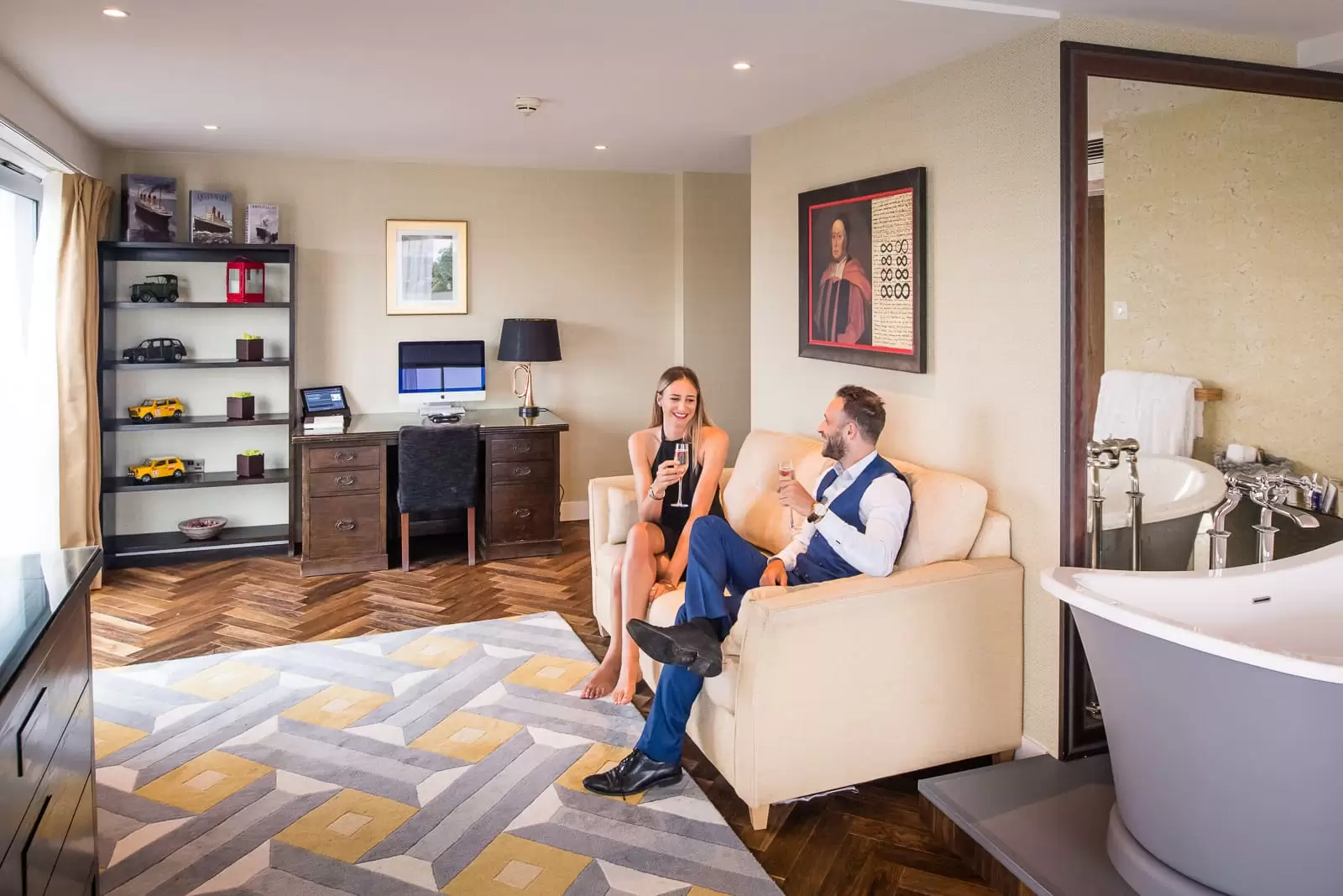 couple in hotel bedroom sitting on sofa ready to go out drinking champagne