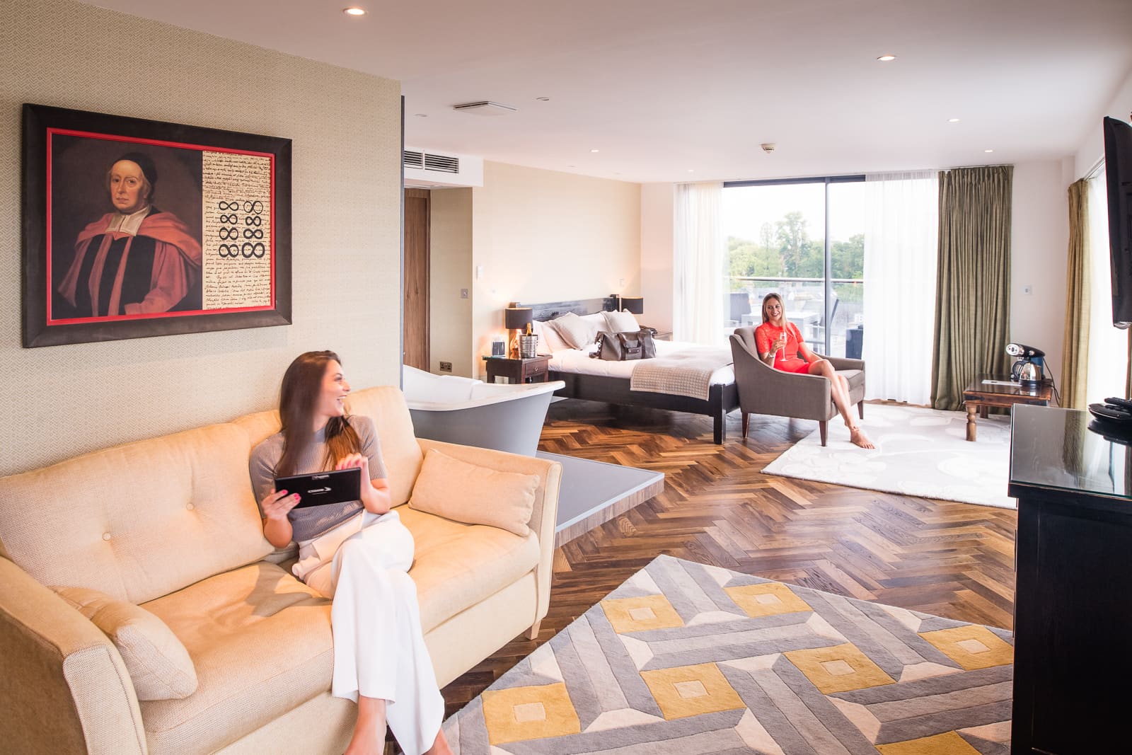 two ladies in hotel bedroom one is looking at the menu the other is drinking champagne