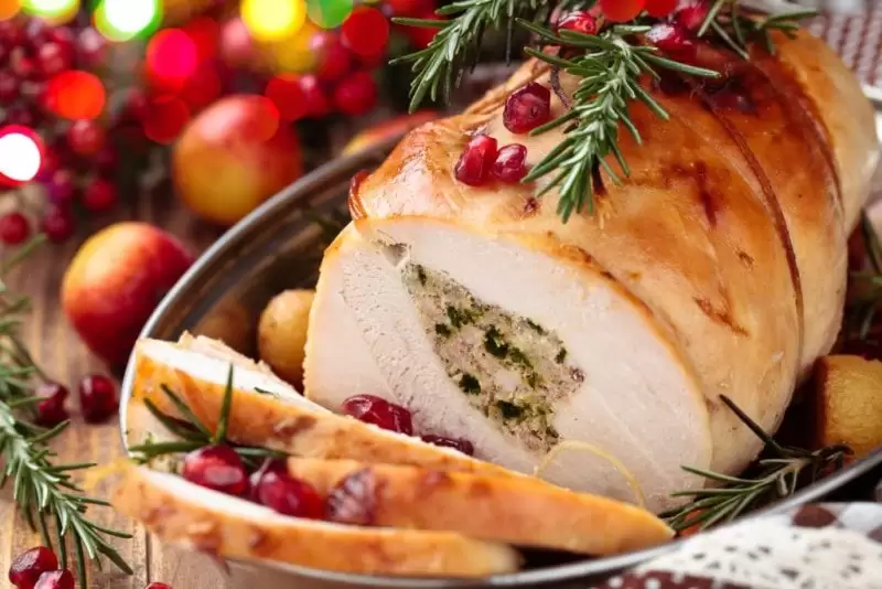 roasted meat with stuffing in the middle and cranberries and rosemary on top. new year's eve