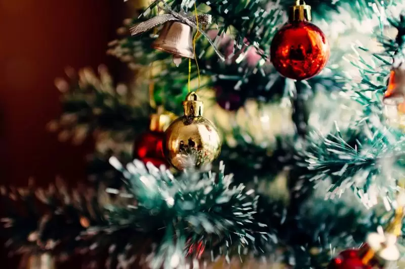 close up of christmas tree with bell and red and gold baubles