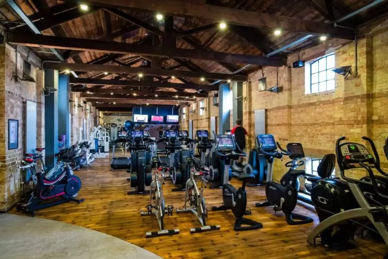 gym with treadmills and bikes with a high ceiling and beams