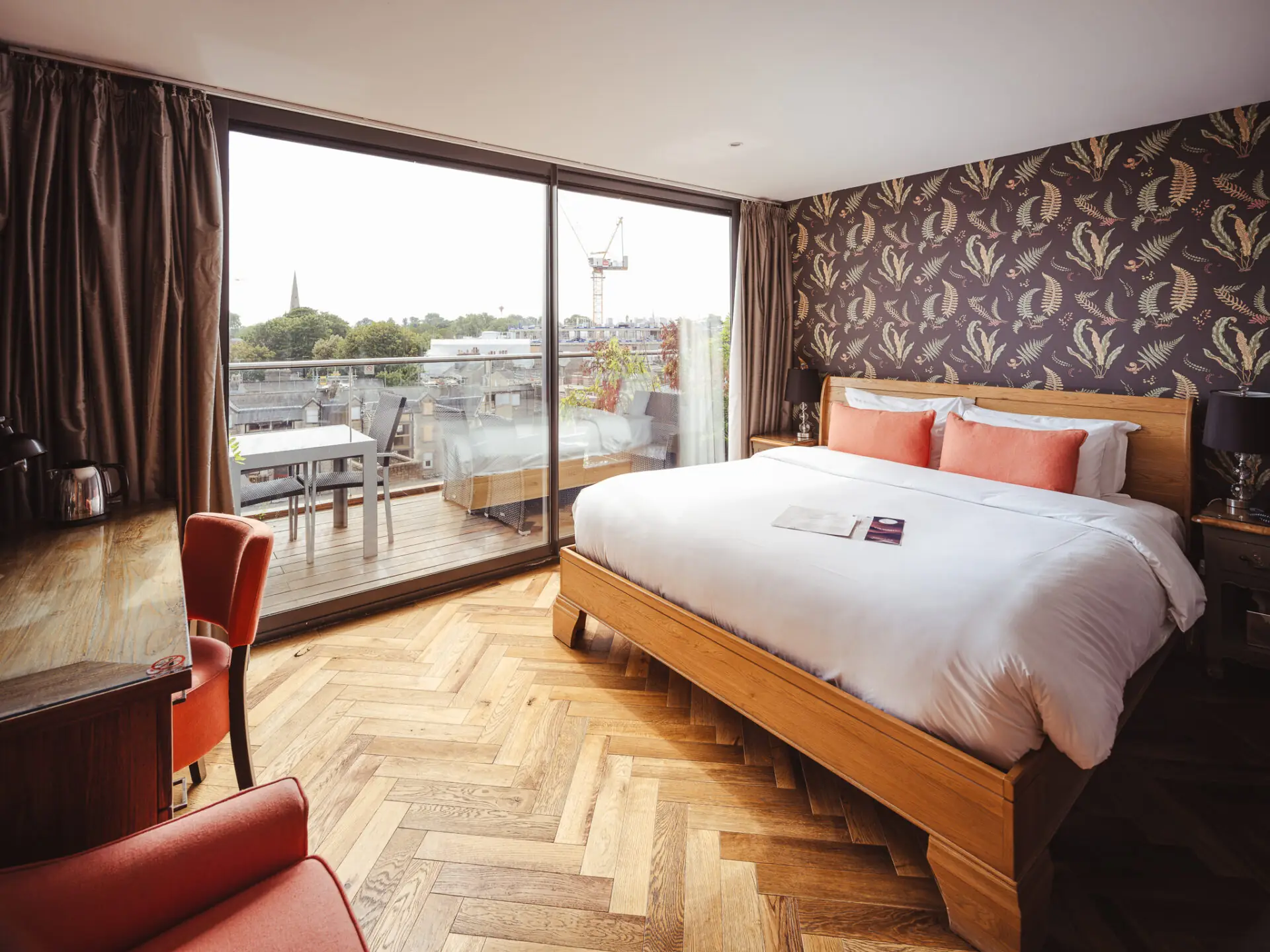 hotel bedroom with dark floral wallpaper and orange soft furnishings
